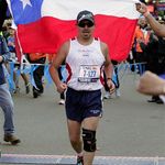 Pena crosses the finish line with a Chilean flag behind him